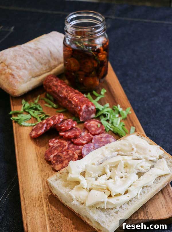 Sliced Brie on ciabatta loaf⁠—prepping spicy salami and roasted tomato sandwich