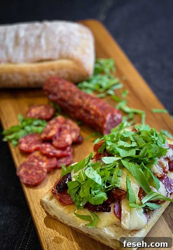 Chopped arugula, roasted tomatoes, spicy salami, and melted brie on ciabatta