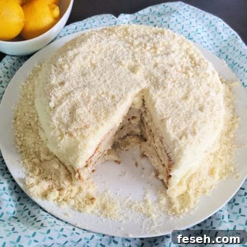 Lemon Cream Cake with a slice cut out of it next to a bowl of lemons