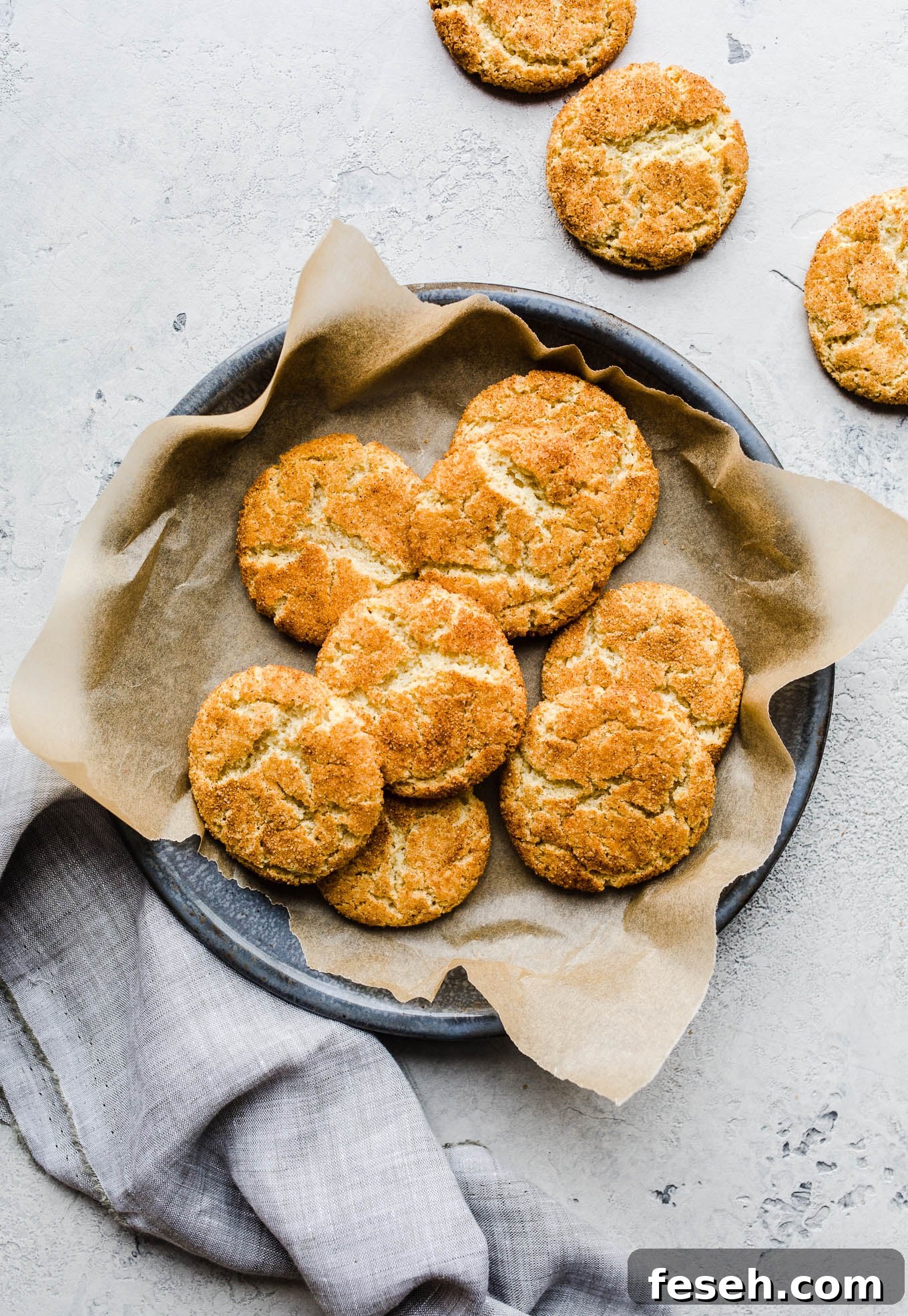 Snickerdoodle cookies on a piece of parchment paper on a blue tray.