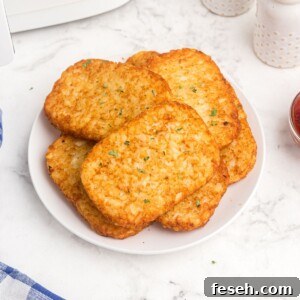 Air fryer hash brown patties on a white plate, served with a side of ketchup.