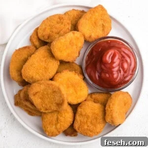 overhead photo of chicken nuggets made in the air fryer served on a white plate with ketchup.
