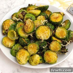 Bright green and crispy brussel sprouts on a white plate sprinkled with parmesan cheese