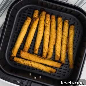 fully cooked taquitos in the air fryer basket in a single layer, ready to be removed and served.