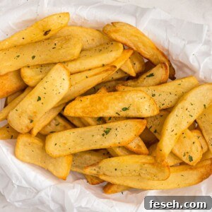 Air fryer steak fries in a basket, garnished with parsley flakes.