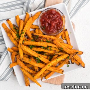 Frozen sweet potato fries made in the air fryer - fully cooked and served on a white plate with a side of ketchup.