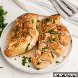 Overhead shot of seasoned chicken breasts made in the air fryer, served on a white plate.