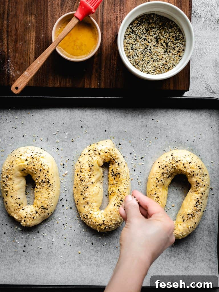 sprinkling everything bagel seasoning on homemade Jerusalem Bagels