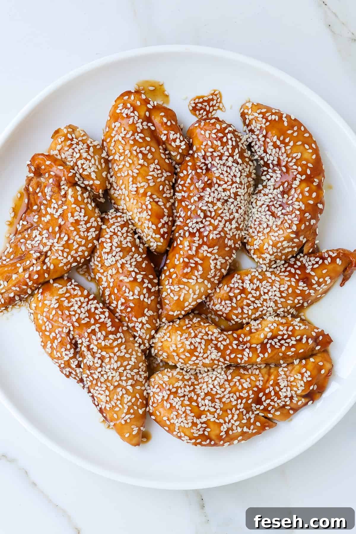 Air fried teriyaki chicken pieces on a plate with sesame seeds sprinkled on top.