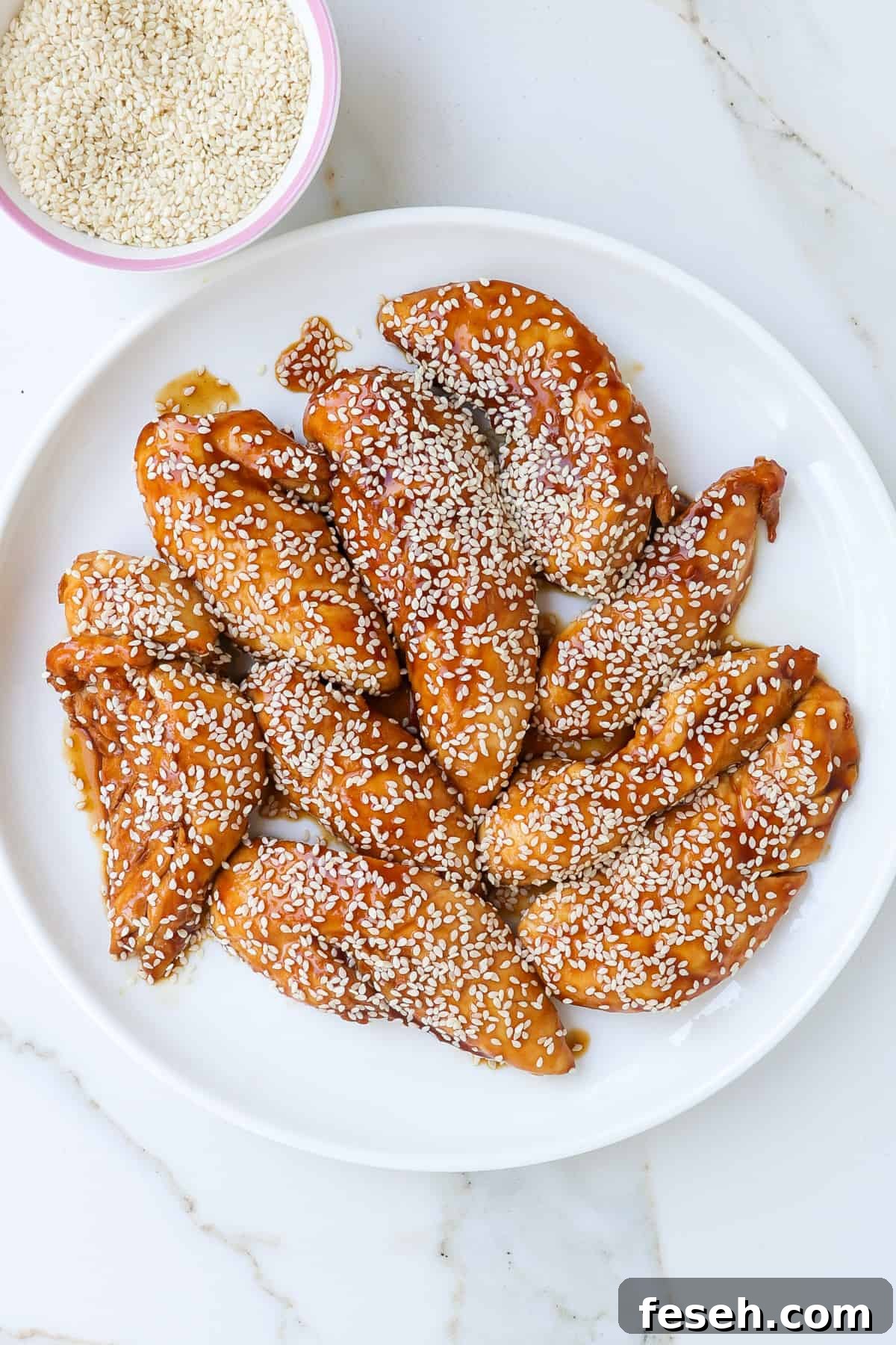 Air fried teriyaki chicken pieces on a plate with sesame seeds sprinkled on top.