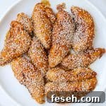 Air fried teriyaki chicken pieces on a plate with sesame seeds sprinkled on top.