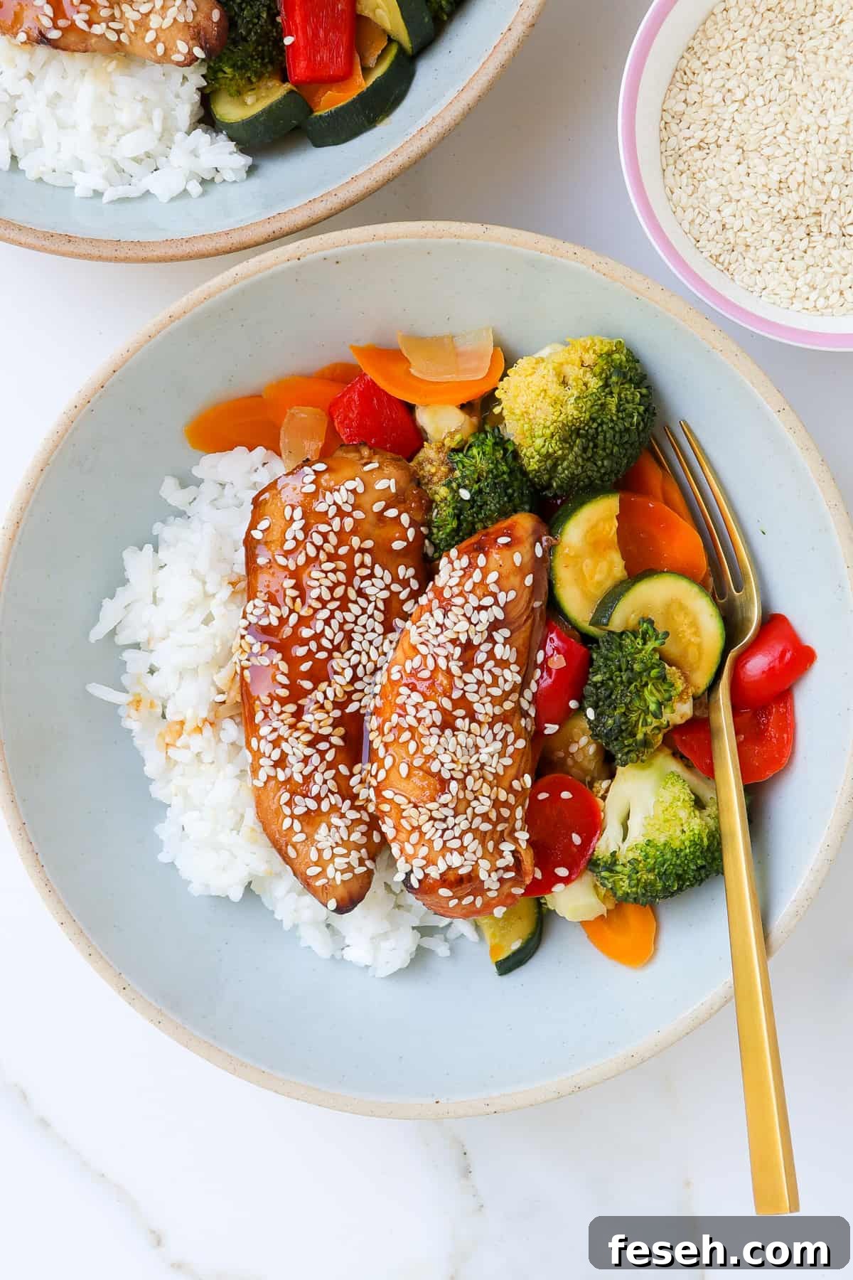 Teriyaki chicken in a bowl with veggies and rice.