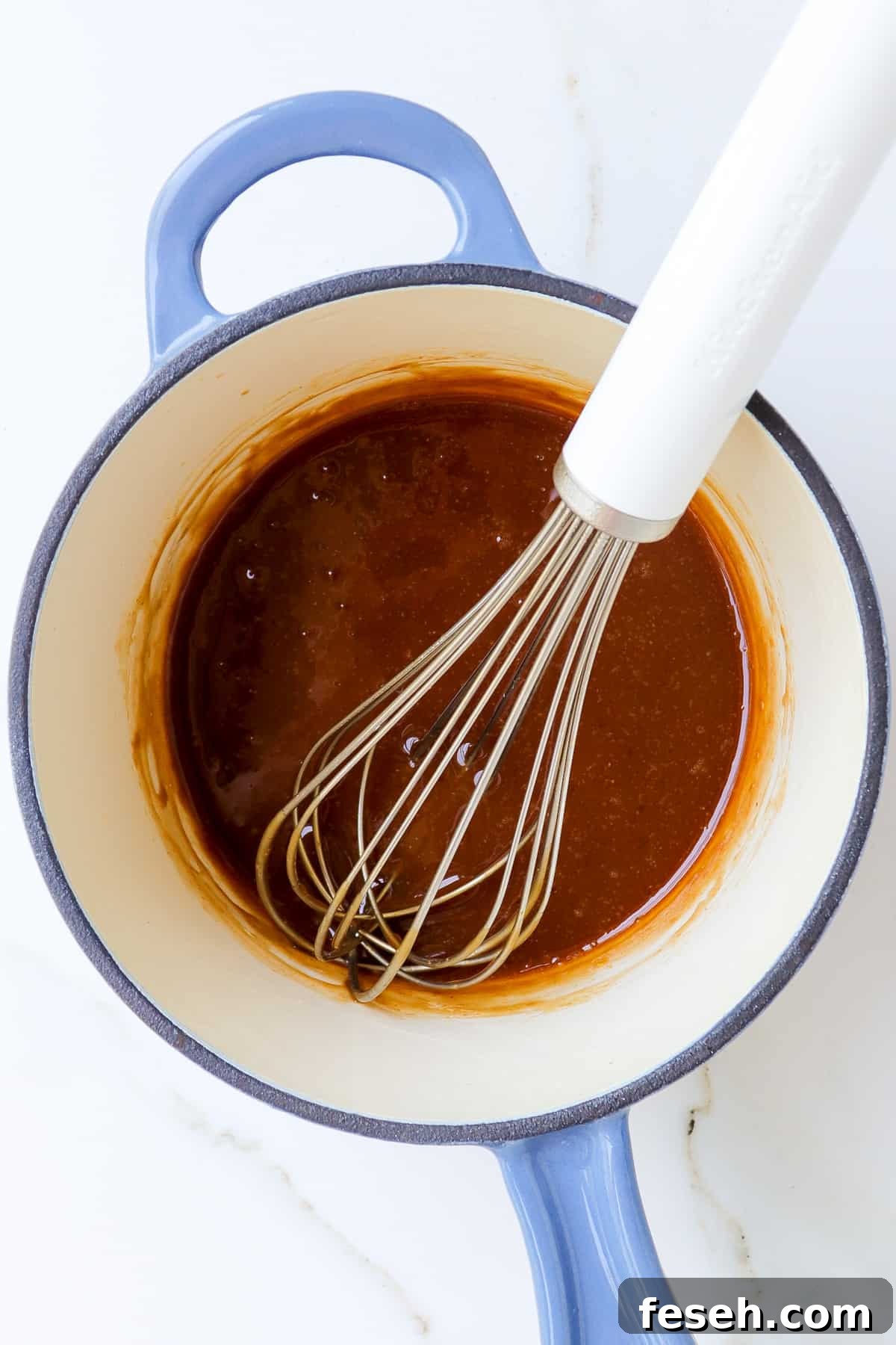 Teriyaki Sauce in a saucepan with a white whisk.