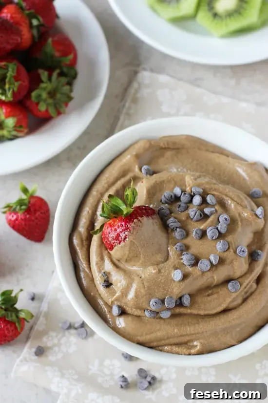 A white bowl filled with Chocolate Avocado Fruit Dip with a strawberry in the dish.