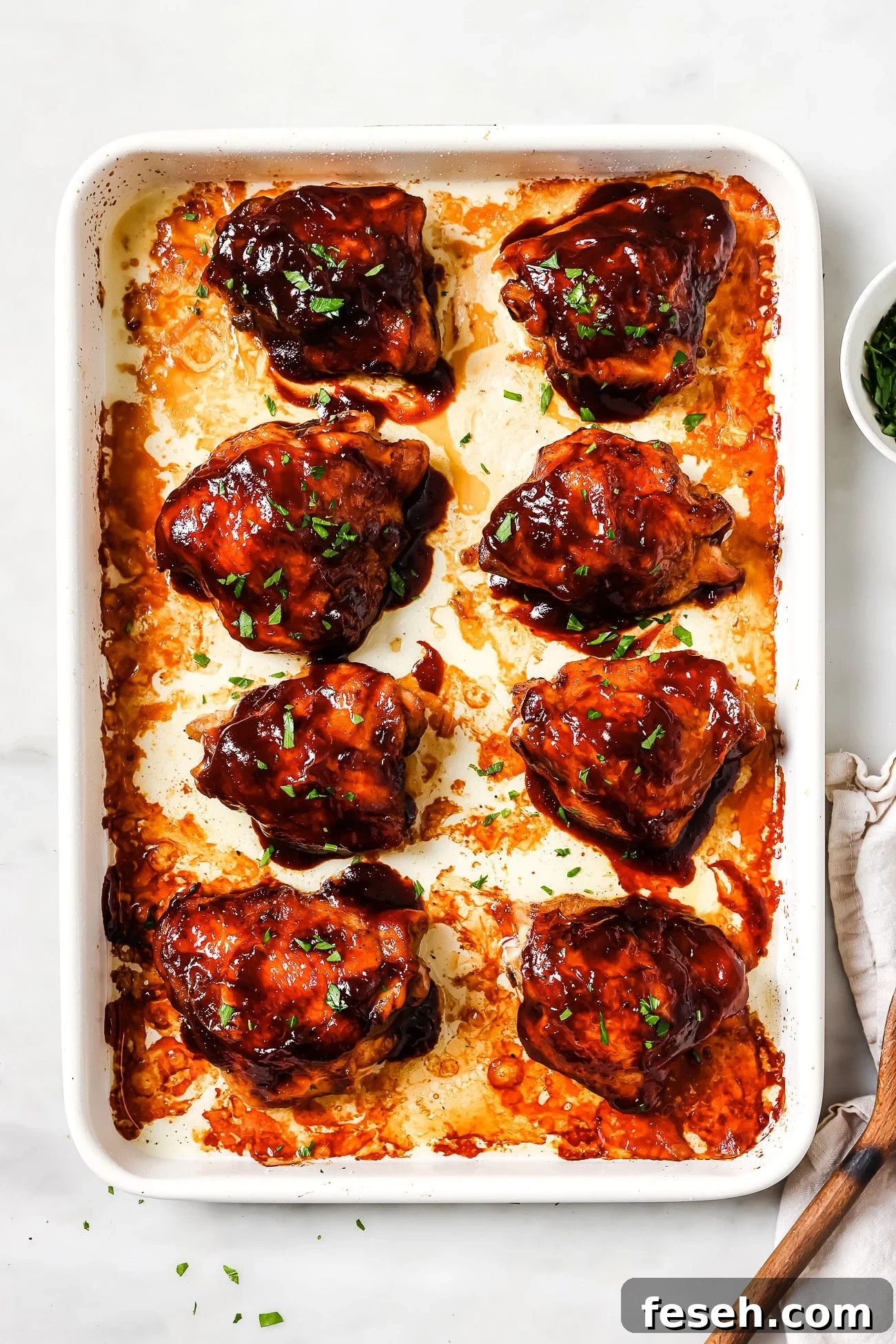 An overhead view of BBQ chicken thighs on a baking sheet.