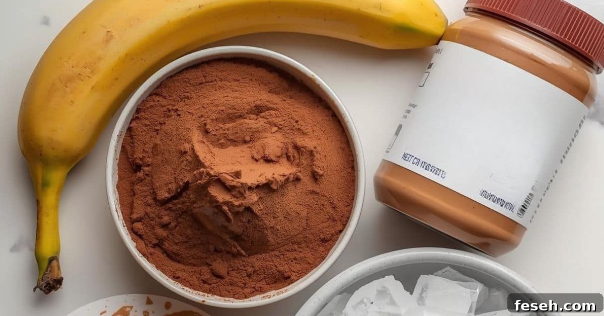 Chocolate Peanut Butter Banana Smoothie Recipe for Creamy Energy 4 A banana, a bowl of cocoa powder, a jar of peanut butter, and a bowl of ice cubes arranged on a white surface—perfect ingredients for a Chocolate Peanut Butter Banana Smoothie.