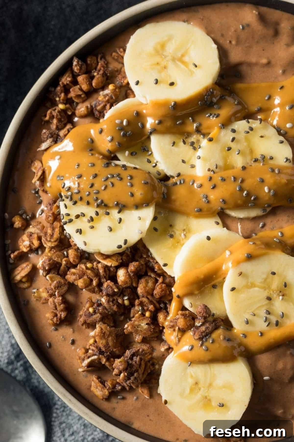 Chocolate Peanut Butter Banana Smoothie Recipe for Creamy Energy 5 A bowl topped with banana slices, granola, chia seeds, and a drizzle of peanut butter.