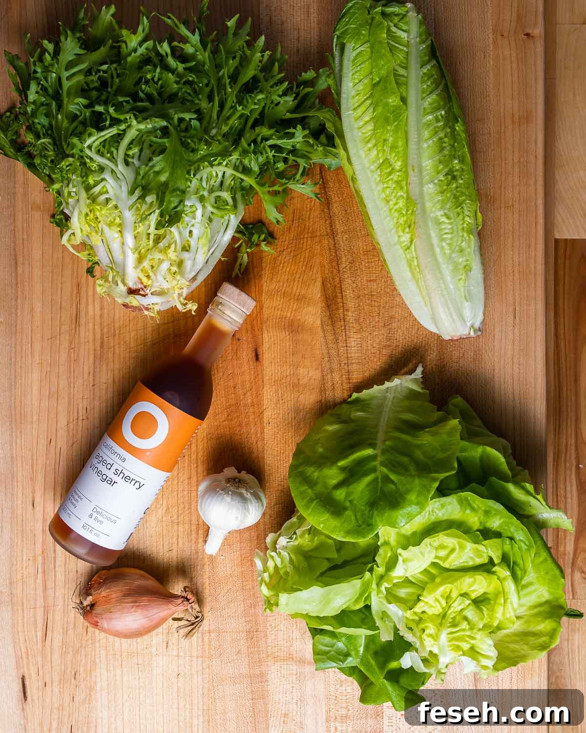 Ingredients shown: frisee, romaine, and Boston lettuce along with bottle of sherry vinegar, head of garlic, and shallot.