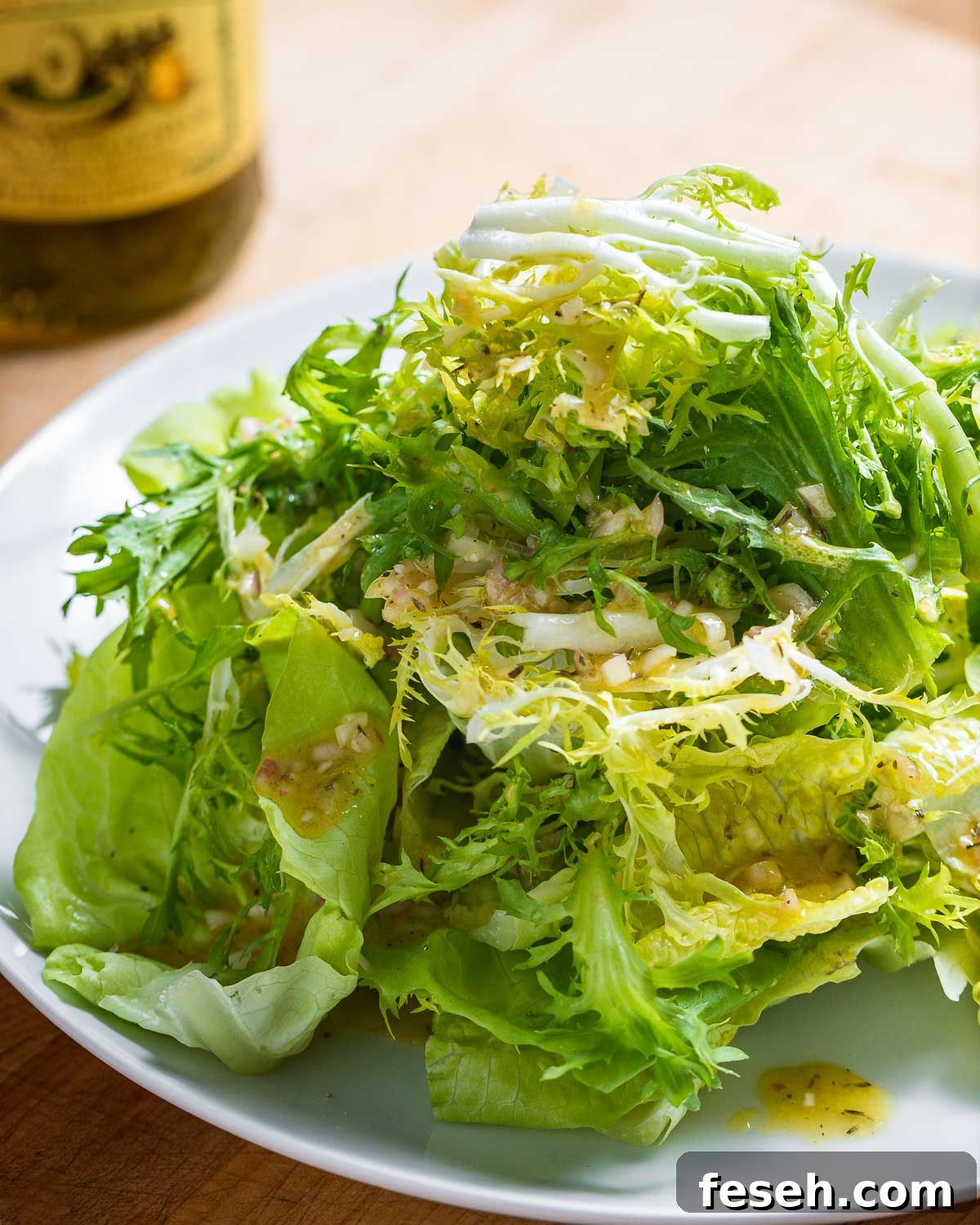 Plate of piled high lettuce greens with vinaigrette.