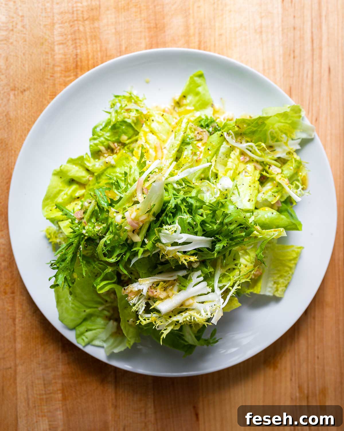 Overhead shot of white plate with 3 types of lettuce.