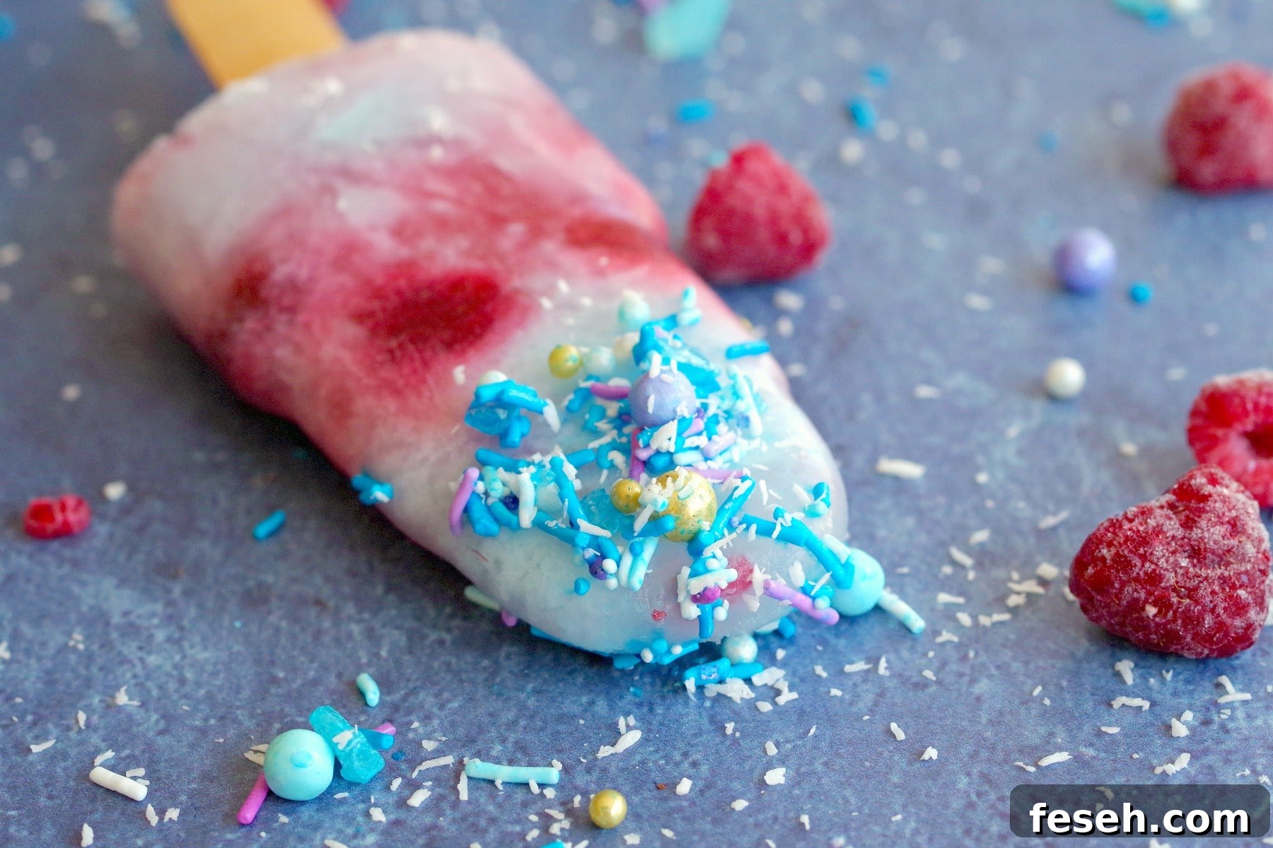 single red white and blue popsicle laying on blue surface with sprinkles