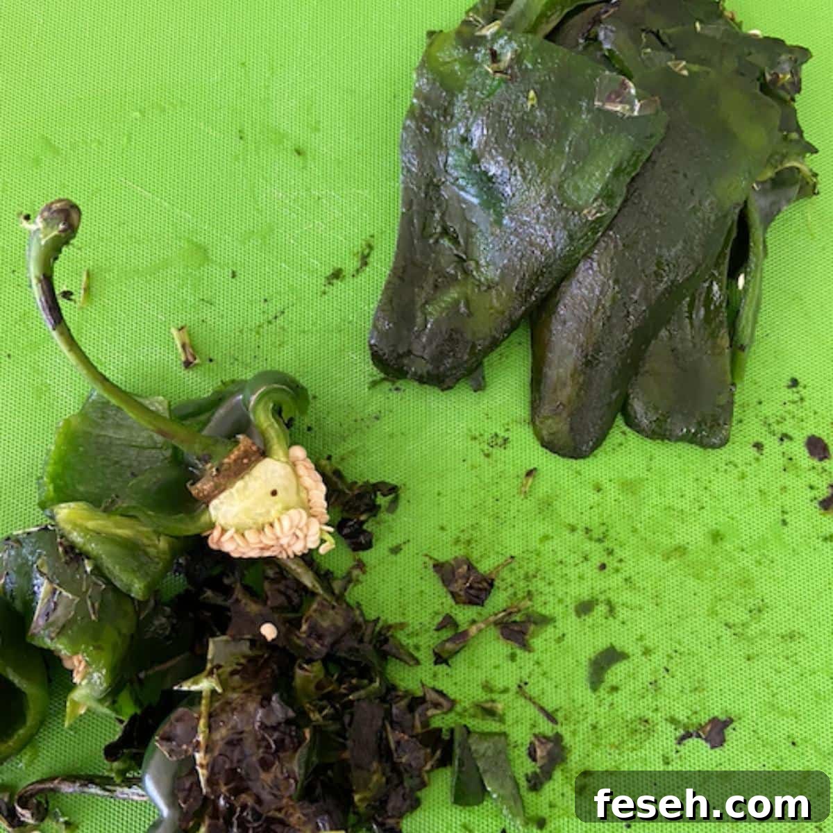 Cutting board with poblanos separated from skin, seeds and stems.