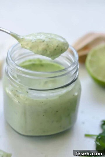 avocado cream sauce in jar with a spoon holding a serving