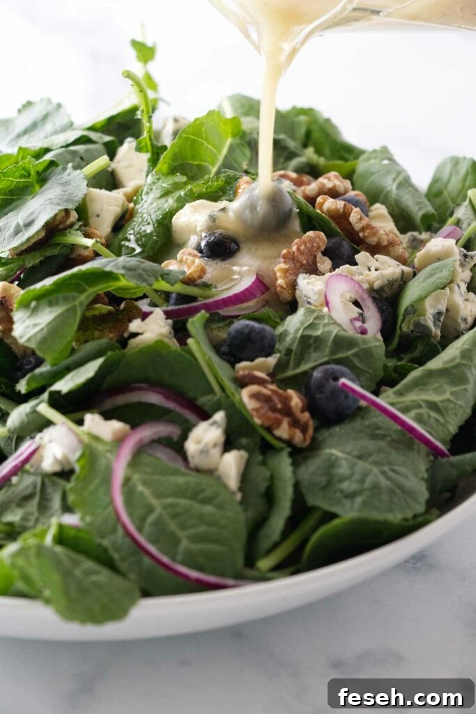 Pouring a lemon vinaigrette on a baby kale salad.