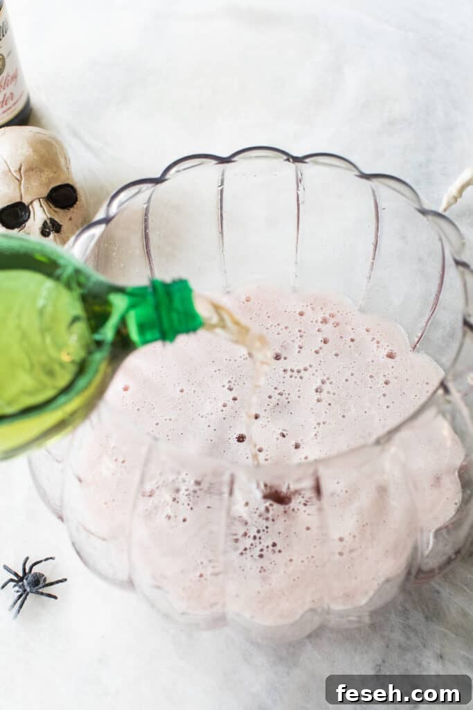pouring ginger ale into a pumpkin punch bowl