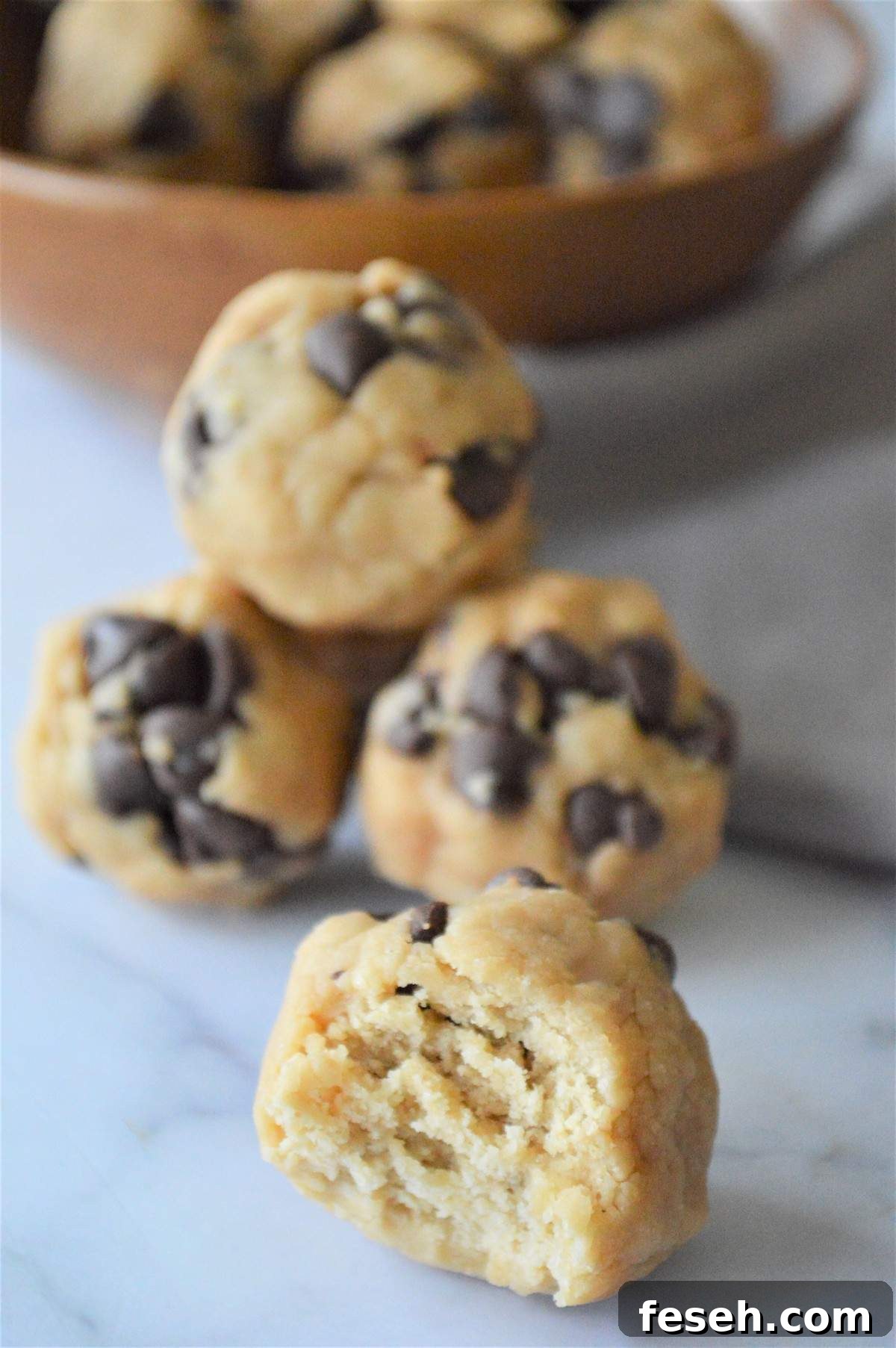 A pile of no bake energy bites with a bowl of extras behind it.