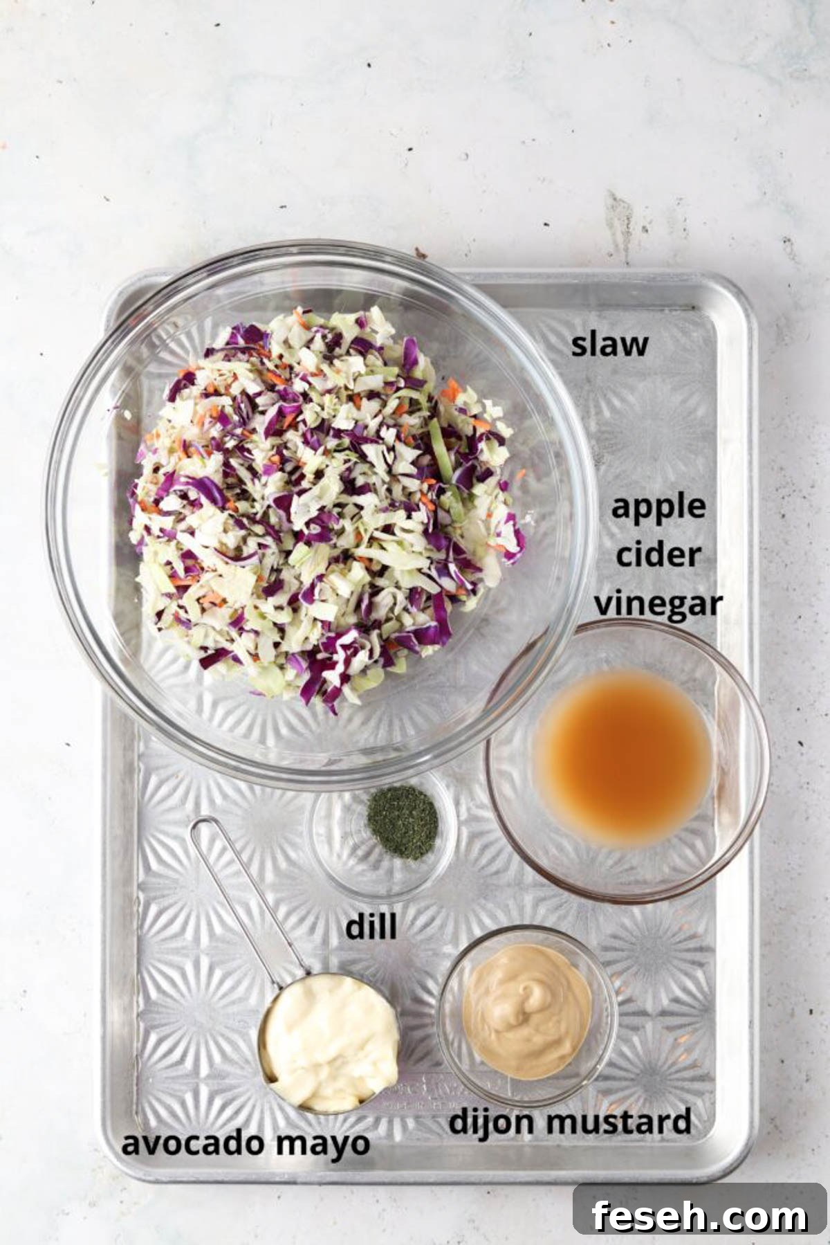 Gluten free coleslaw ingredients in small glass bowls on a silver tray.