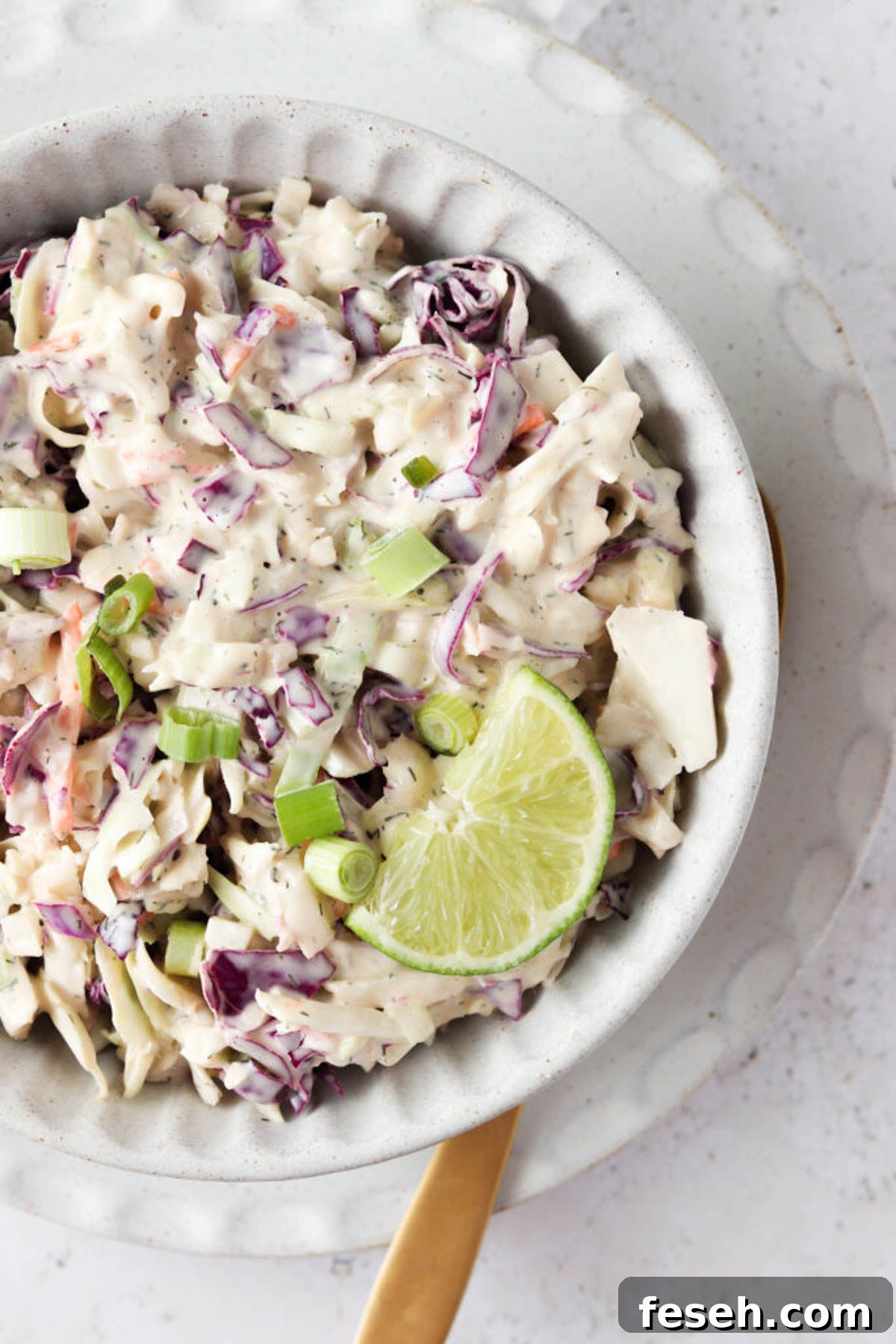 Gluten free coleslaw in a clay bowl with a fresh lime slice.