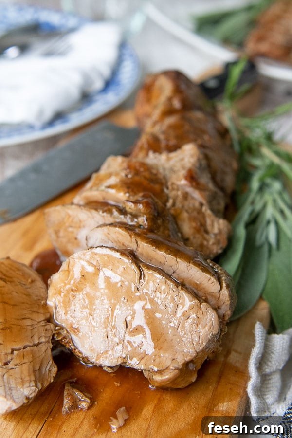 cut pieces of pork tenderloin on a wooden cutting board with sauce drizzled over