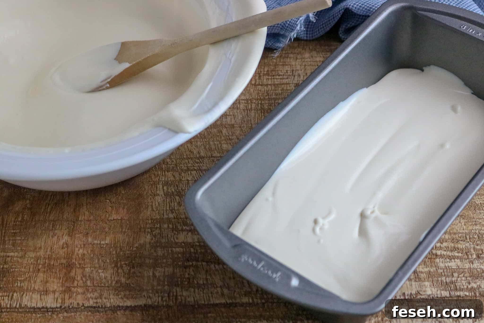 White bowl with No-Churn Ice Cream and wooden spoon next to a silver pan half-filled with No-Churn Ice Cream
