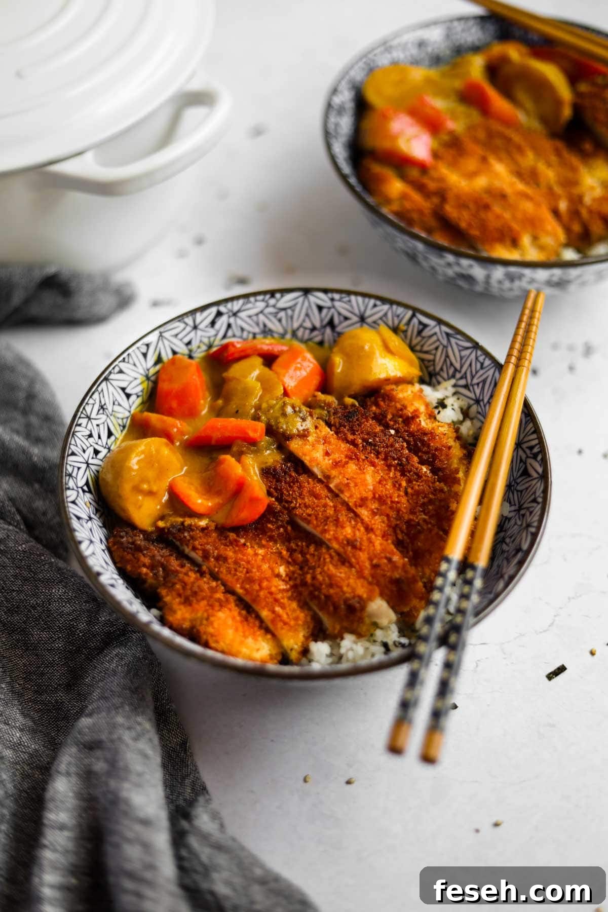 Chicken Katsu Curry in a blue Japanese porcelain bowl with blue and wood bamboo chopsticks and a white Le Creuset dutch oven