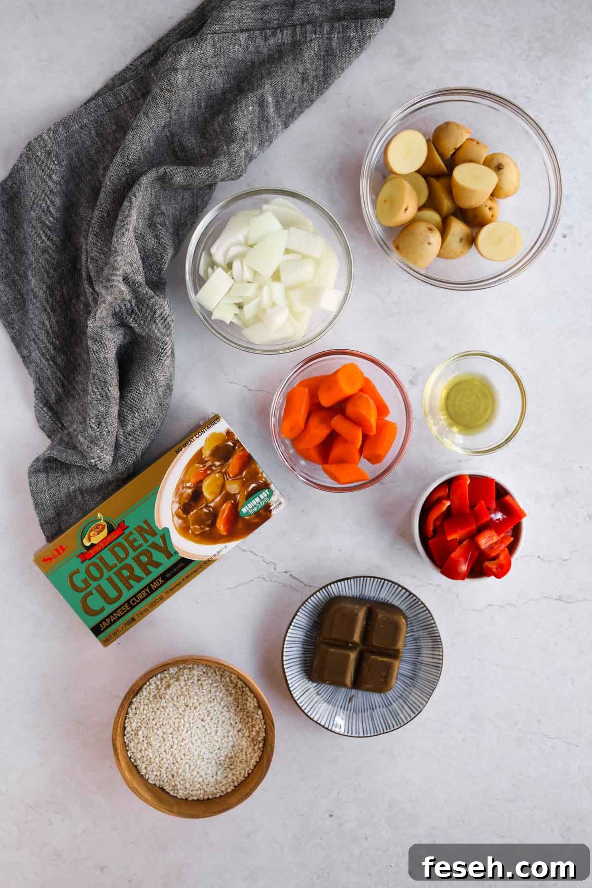 Katsu Curry Ingredients in glass bowls, including chopped onion, carrot, bell pepper, potatoes, golden curry blocks, and rice