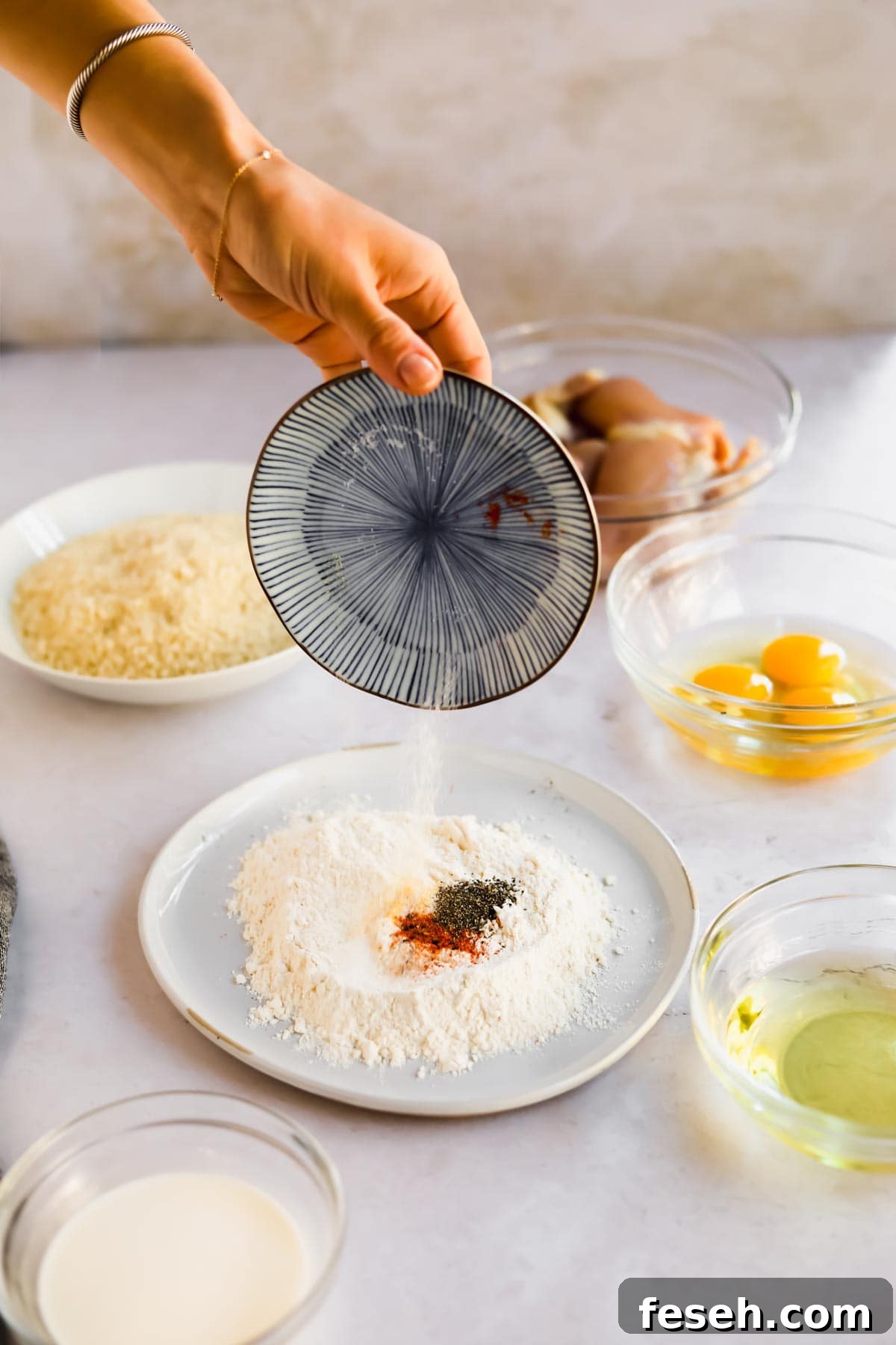 Hand pouring seasoning into flour for Chicken Katsu dredge mixture