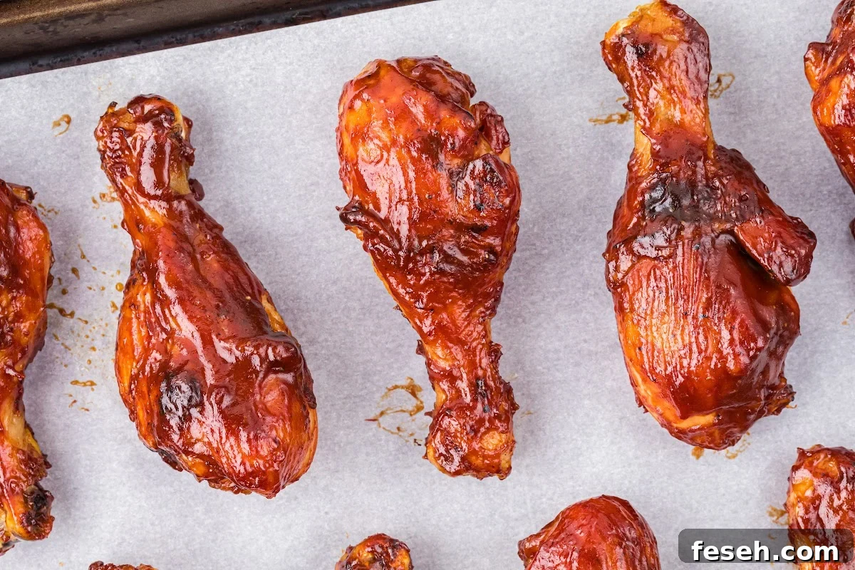 cooked chicken drumsticks with barbecue sauce on baking sheet.