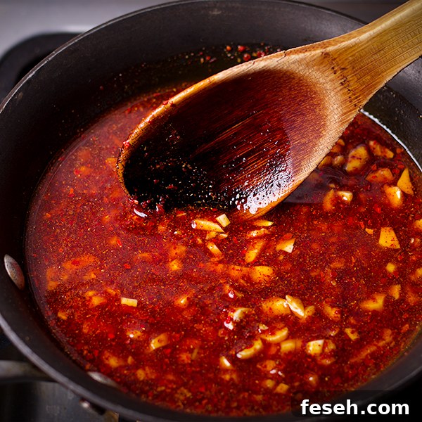 Stirring crispy garlic and Aleppo pepper chili oil in a small saucepan.