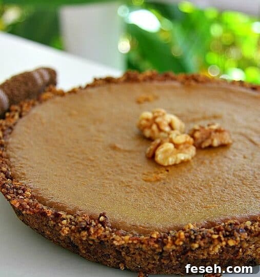 A round walnut pumpkin pie with a nutty crust, topped with whole walnuts, is displayed on a white plate.