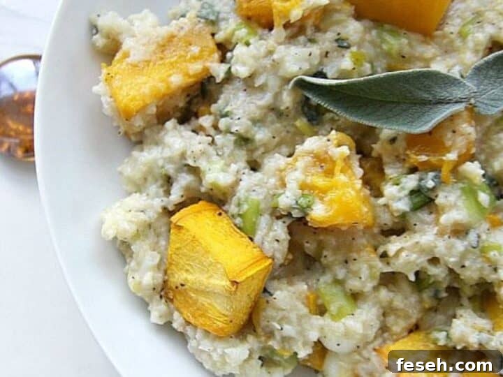 A plate of pumpkin cauliflower risotto topped with pieces of roasted butternut squash and garnished with a fresh sage leaf.