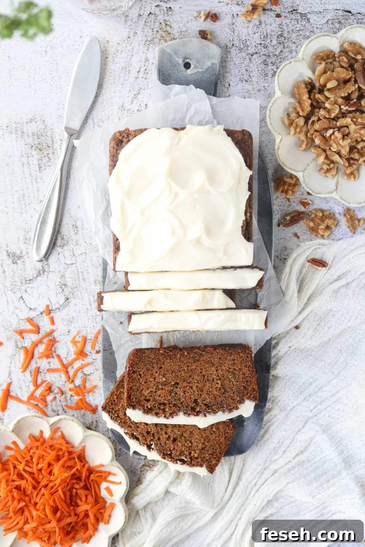 Sliced carrot cake on a marble cutting board.