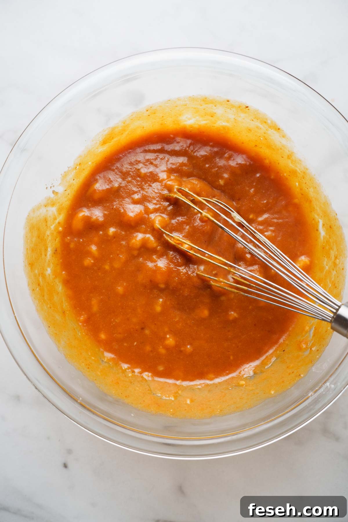 wet ingredients for pumpkin banana bread muffins in a bowl with whisk.