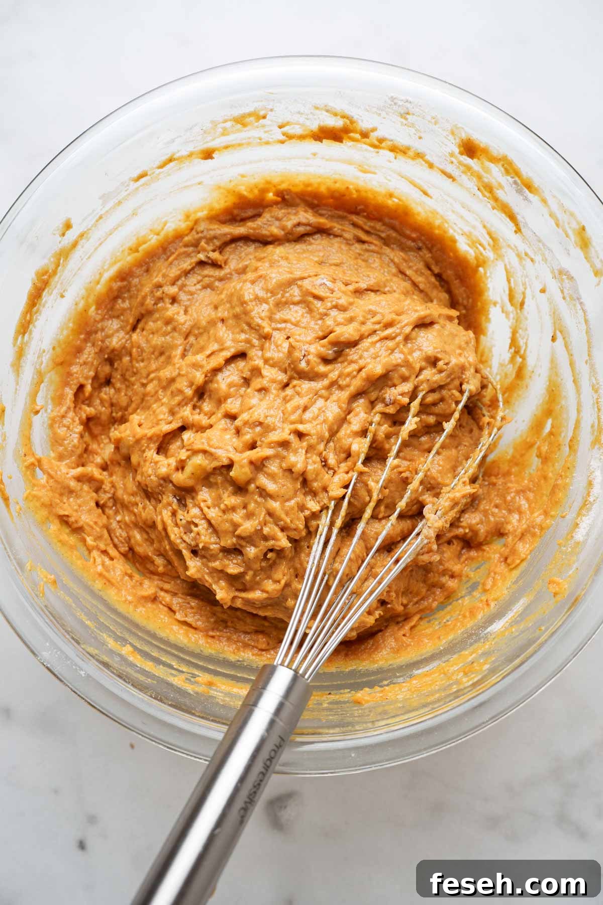 batter for the pumpkin banana bread muffins in a bowl with a whisk.