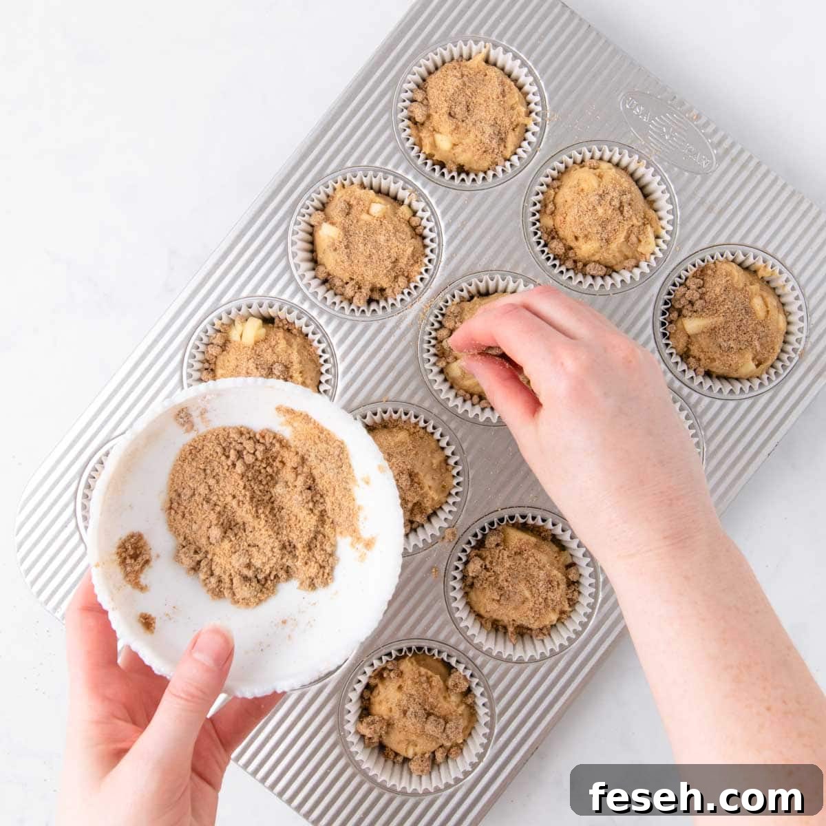 The crumble topping being sprinkled on top of the muffin batter.