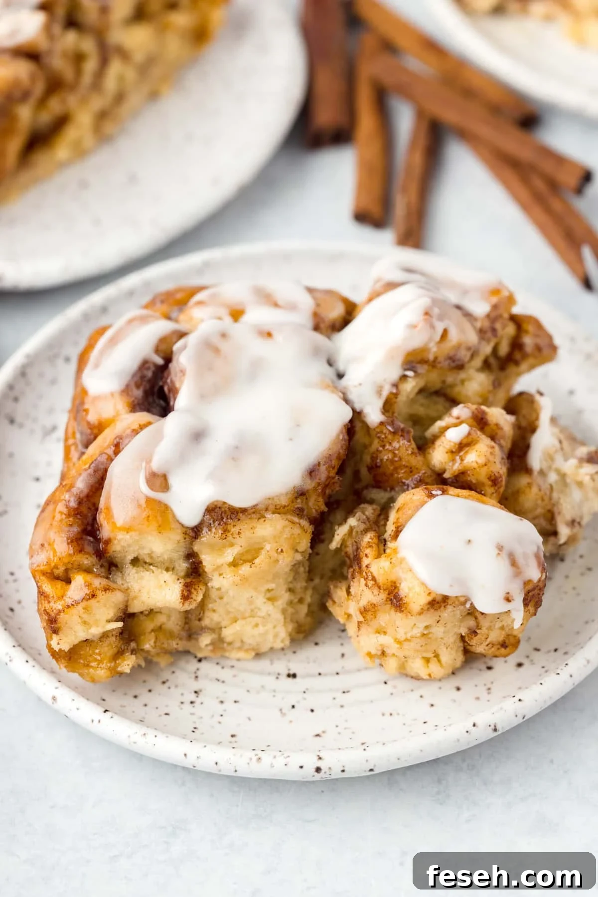 A cinnamon roll on a plate, topped with icing.
