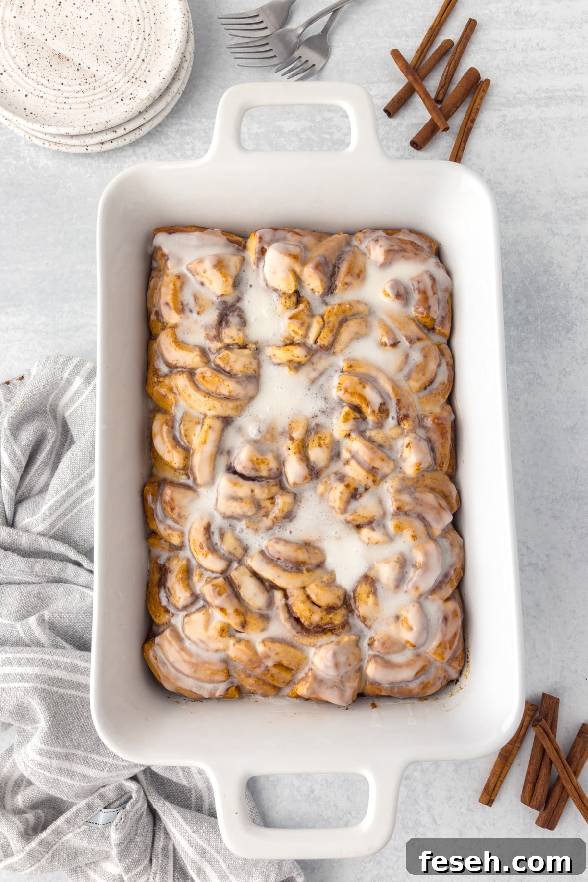 A baking dish filled with cinnamon roll bake, topped with icing.