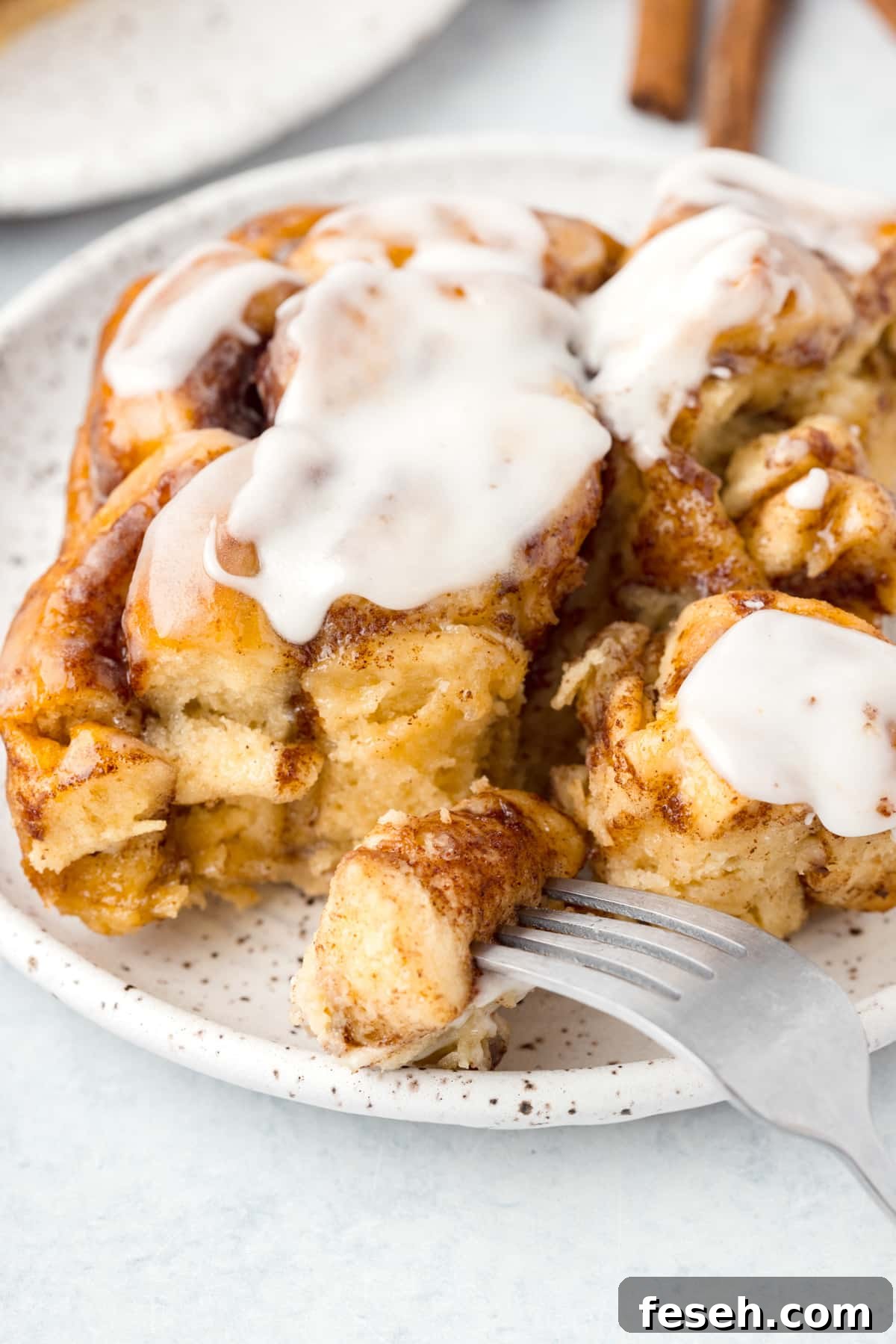A fork taking a portion from a cinnamon roll.