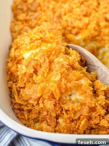 Scooping a small amount of hash brown casserole with a wooden spoon.