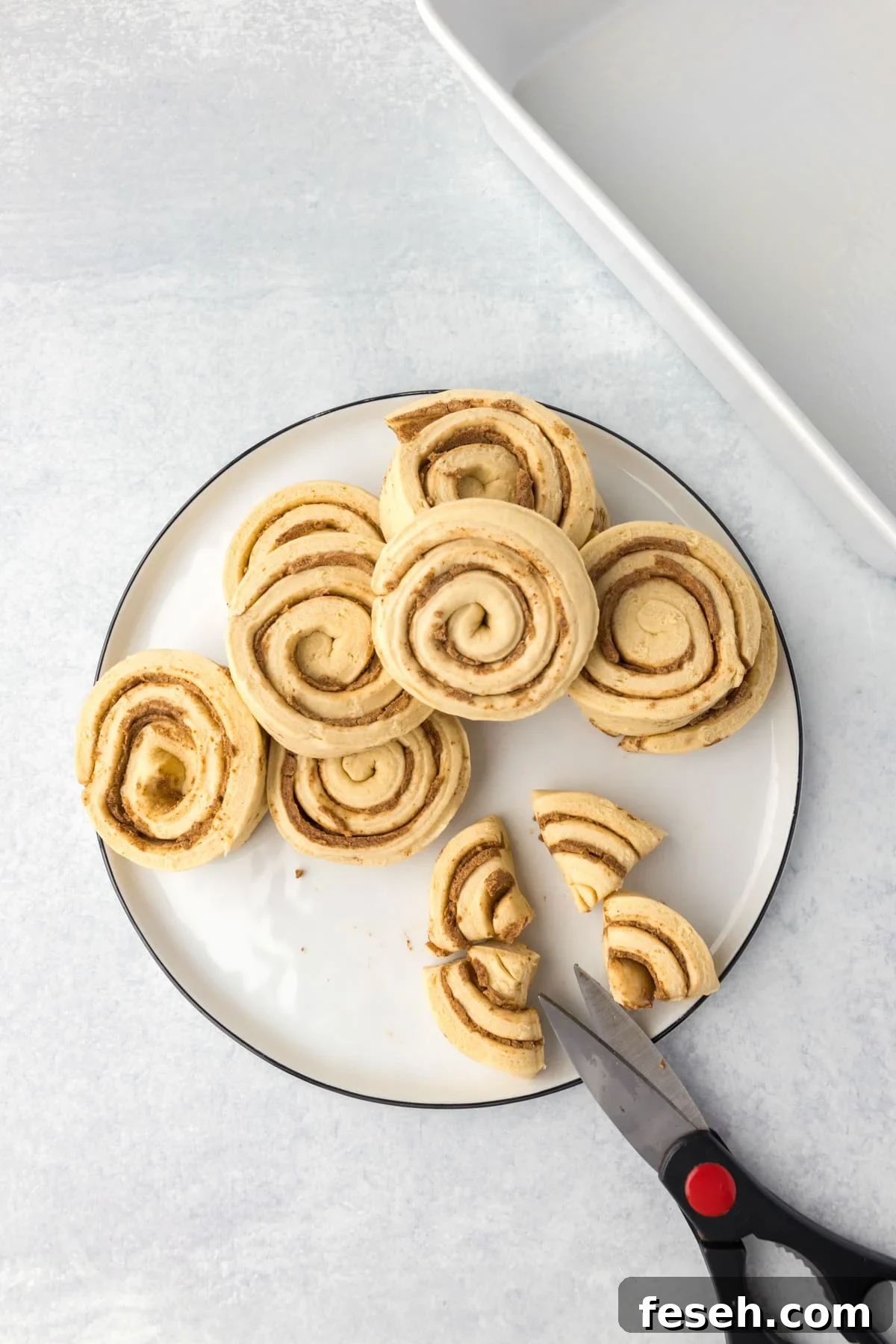 Slicing cinnamon rolls into quarters with scissors.